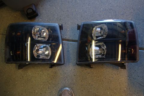 2007 Chevrolet Silverado 1500 - Aftermarket black headlights are shown laid out on a garage floor, ready for installation.