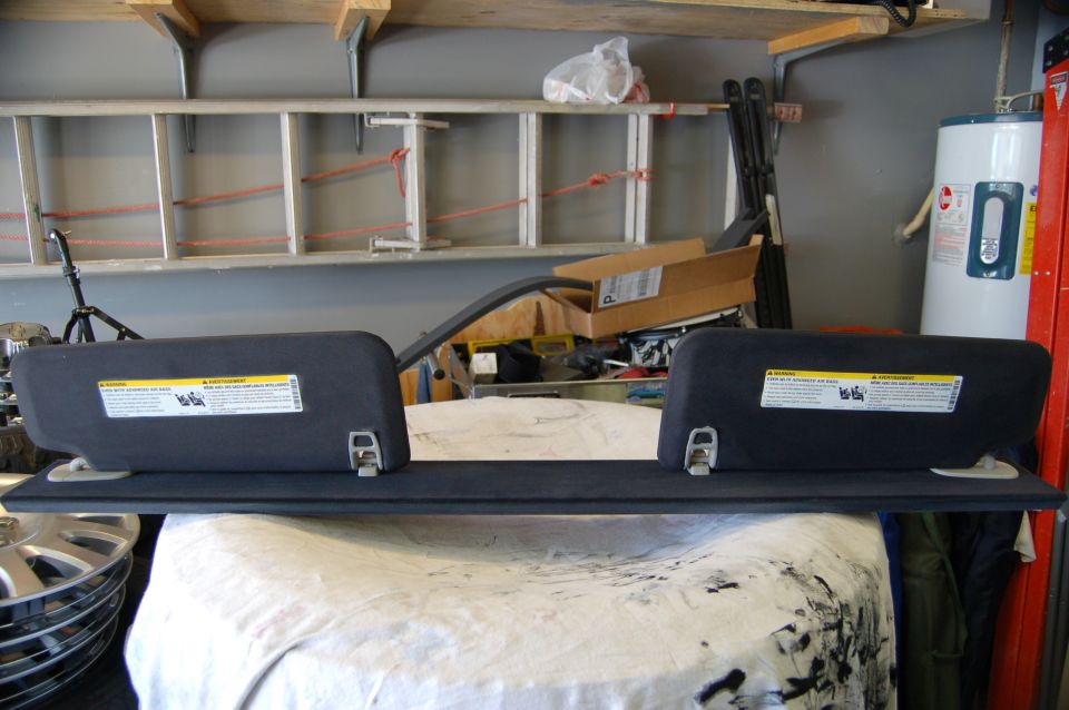Two dark gray sun visors with warning labels attached, resting on a surface