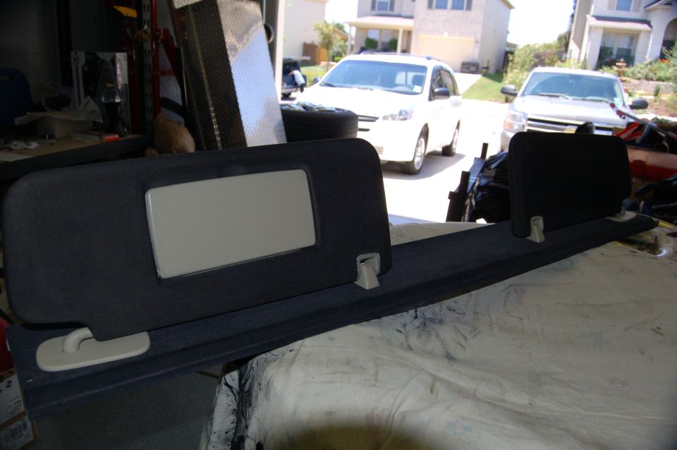 Dark gray fabric sun visor with a beige mirror panel and a long, dark gray trim piece with mounting clips