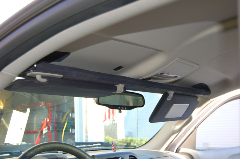 Interior shot of a vehicle's overhead console and sun visors, with a rearview mirror visible