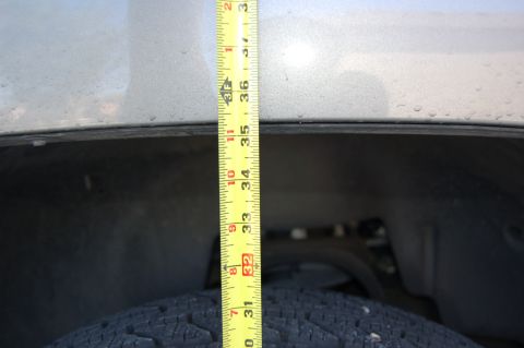 2007 Chevrolet Silverado 1500 - Measuring suspension height with a tape measure. The measurement is approximately 33 inches.