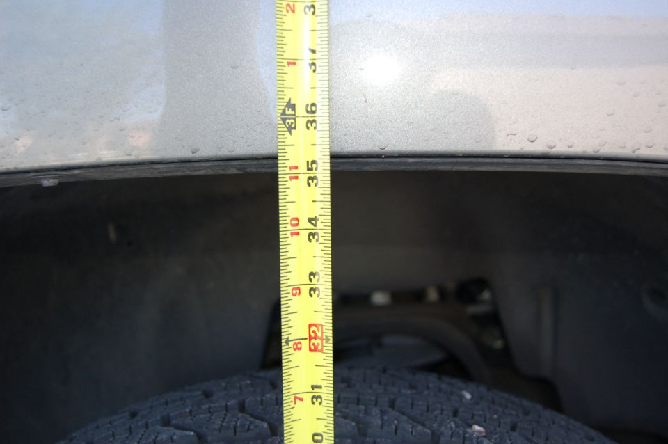Tape measure showing height above tire, likely suspension measurement