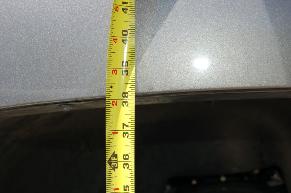 Yellow measuring tape showing 36 to 41 inches against a silver vehicle's body panel