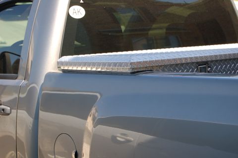 2007 Chevrolet Silverado 1500 - A diamond plate toolbox is mounted on the bed of a pickup truck. An 'AK' sticker is visible on the rear window.