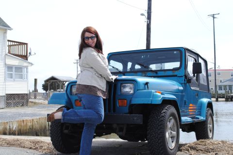 1991 Jeep YJ - Woman poses with a blue 1991 Jeep YJ near a beach house.