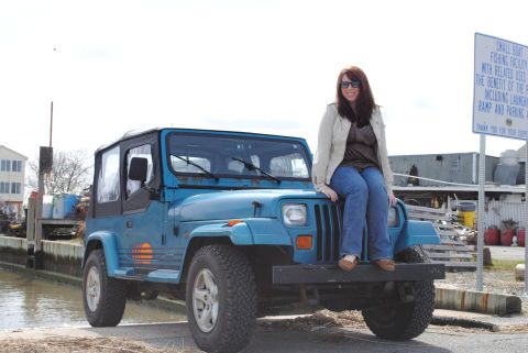 1991 Jeep YJ - A blue 1991 Jeep YJ is parked by the water with a woman on its hood.