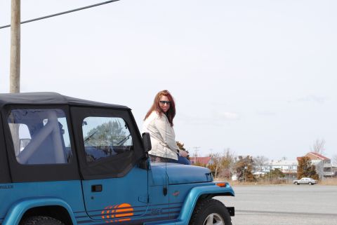 1991 Jeep YJ - Woman sits on the hood of a blue 1991 Jeep YJ Wrangler.