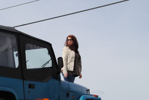 1991 Jeep YJ - A woman poses on the hood of a blue Jeep Wrangler against a clear sky.