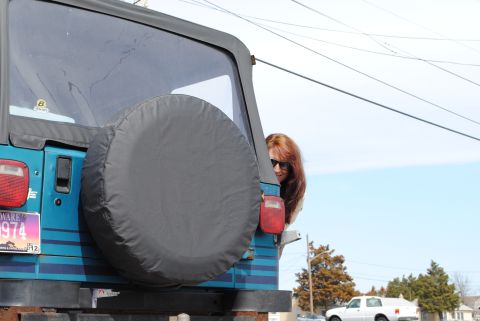 1991 Jeep YJ - Rear view of a teal 1991 Jeep YJ with a spare tire and a woman peeking out.