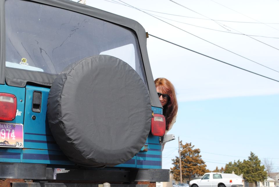 1991 Jeep YJ rear view, teal body, spare tire cover, woman looking out window, Delaware license plate 0974