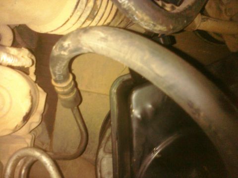 1995 Ford Bronco - A close-up view of a power steering pump hose and reservoir within an engine bay.
