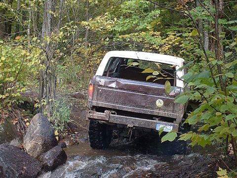 1978 Ford Bronco - This SUV navigates a rocky stream bed surrounded by autumn foliage.
