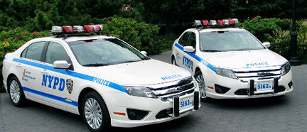 1991 Ford LTD Crown Victoria - Two NYPD police cruisers are shown parked together, displaying their official markings and emergency lights.