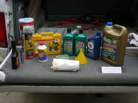 1988 Ford Bronco - Collection of automotive fluids and tools organized in the cargo area of a vehicle.