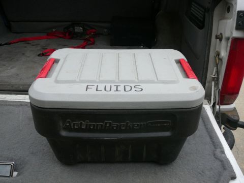 1988 Ford Bronco - A storage container labeled 'FLUIDS' sits in the cargo area of a vehicle.