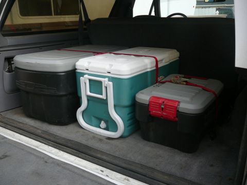 1988 Ford Bronco - Coolers are strapped down in the cargo area of a vehicle.