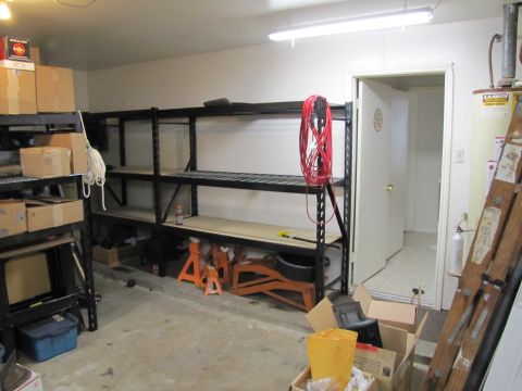1993 Ford F-250 - A cluttered garage scene with shelves filled with boxes and various tools, including jack stands and a ladder.