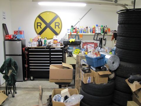 1993 Ford F-250 - A cluttered garage scene contains a tool chest, refrigerator, stacked tires, and a railroad crossing sign on the wall.