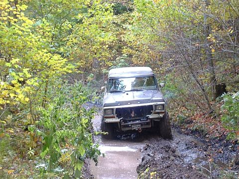 1978 Ford Bronco - This Ford Bronco navigates a challenging muddy path surrounded by autumn trees.