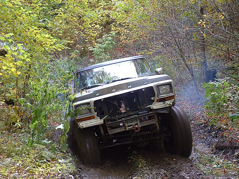 1978 Ford Bronco navigating a muddy trail with smoke coming from the exhaust