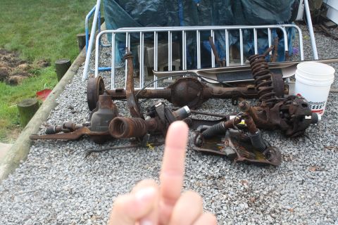 1996 Ford Bronco - Vehicle suspension and axle parts are piled on the ground, possibly for a rebuild or tear-down.
