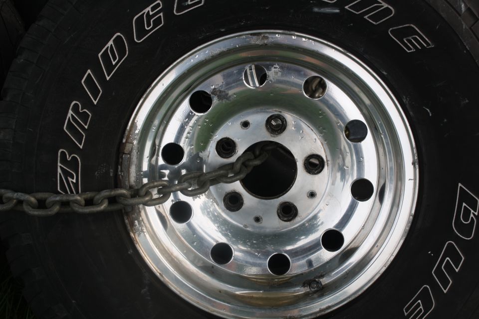 Close-up of a tire with 'BRIDGESTONE' text and a chrome wheel secured by a chain