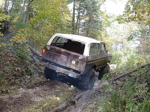 1978 Ford Bronco - This 1978 Ford Bronco is navigating a muddy, wooded trail, showing its off-road capabilities.