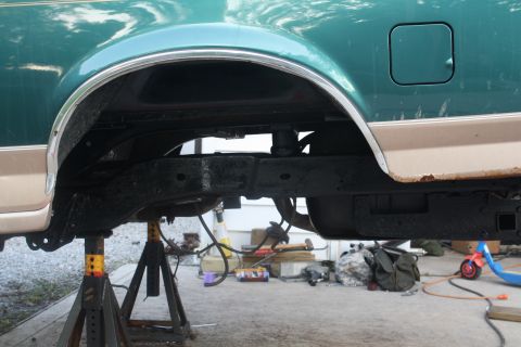 1996 Ford Bronco - Underside view of a 1996 Ford Bronco undergoing maintenance, with the rear axle supported by jack stands.