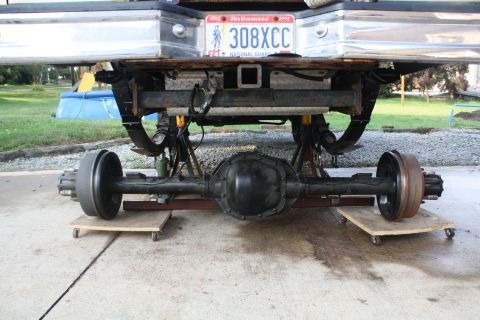 1996 Ford Bronco - The rear axle assembly of a vehicle is supported by dollies and jack stands, with a license plate visible above.