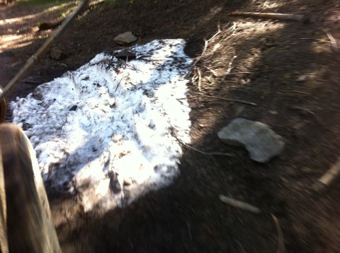 1990 Ford Bronco - A patch of snow melts on a dirt path, with a tire visible on the left and the Supermotors.net logo in the lower right corner.