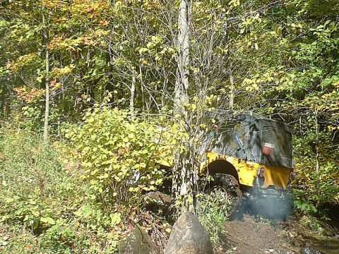 1978 Ford Bronco - A yellow off-road vehicle navigates a muddy trail surrounded by autumn foliage.
