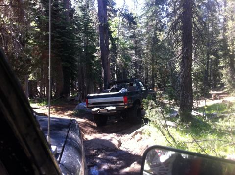 1990 Ford Bronco - A 1990 Ford Bronco navigates a rough, wooded path during an off-road excursion.