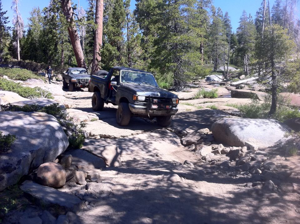 Dark gray Ford F-Series truck with off-road tires navigating a rocky trail