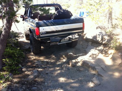 1990 Ford Bronco - This Ford Bronco is tackling a rough, rocky path in a wooded area.