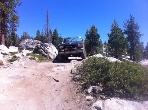 1990 Ford Bronco - This 1990 Ford Bronco navigates a challenging rocky path under a clear blue sky.