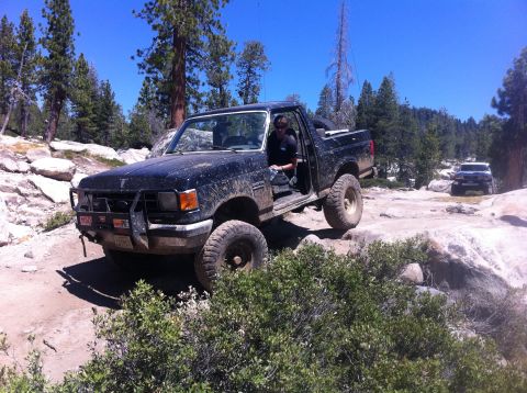 1990 Ford Bronco - A black Ford Bronco navigates a rocky mountain trail with another vehicle following behind.