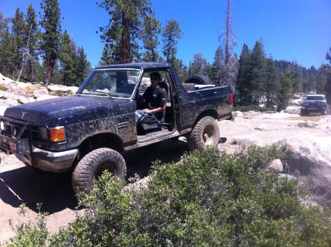 1990 Ford Bronco - A black 1990 Ford Bronco navigates a rocky trail with another SUV following behind.