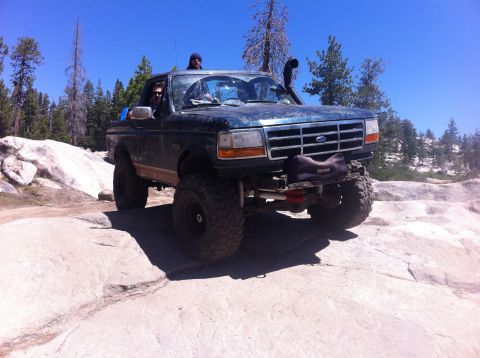1990 Ford Bronco - This modified Ford Bronco navigates rocky terrain, equipped with a snorkel for off-road adventures.