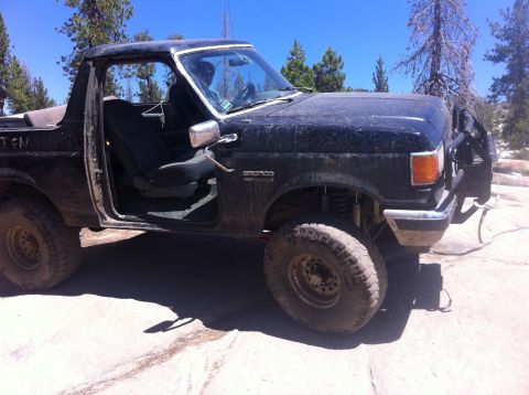 1990 Ford Bronco - This 1990 Ford Bronco is parked on a rocky, dirt surface with trees in the background.
