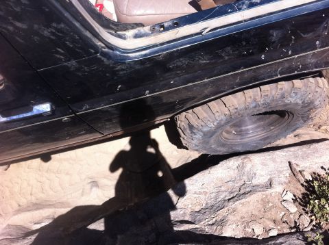 1990 Ford Bronco - A vehicle navigates a rocky trail, with its tire angled on a large boulder.