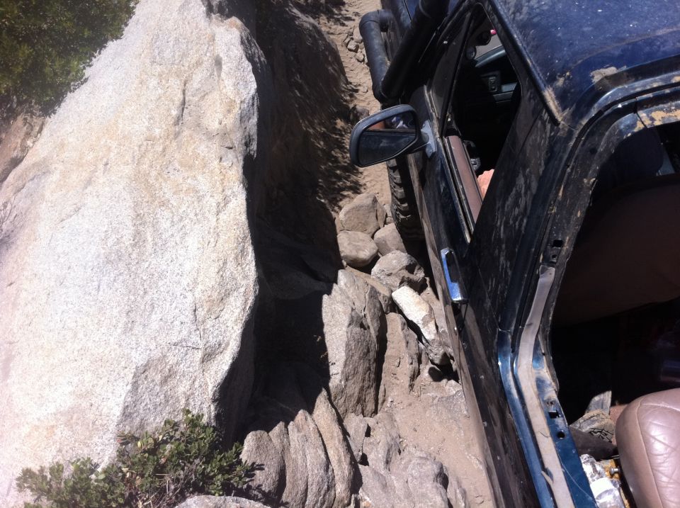Black SUV with open door on rocky trail