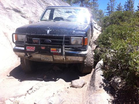 1990 Ford Bronco - A black Ford Bronco navigates a challenging rocky terrain on an off-road trail.