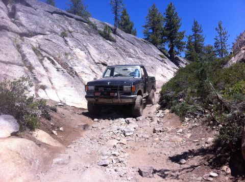 1990 Ford Bronco - A black 1987 Ford Ranger navigates a challenging rocky trail under a clear blue sky.