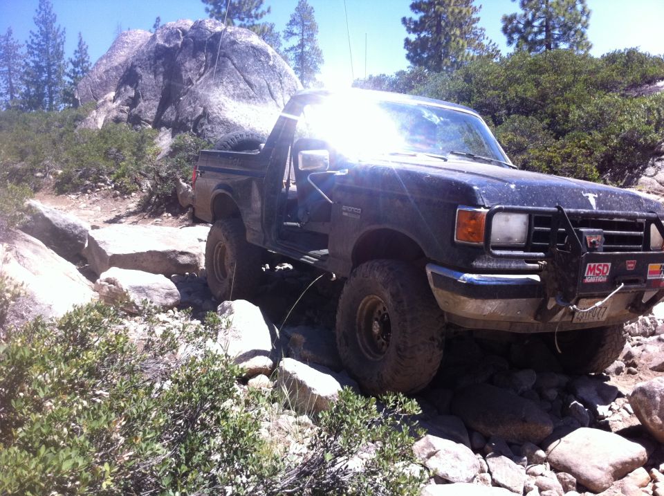 1990 Ford Bronco navigating rocky terrain, front bull bar with MSD sticker