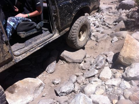 1990 Ford Bronco - This black SUV navigates a challenging rocky path, demonstrating its off-road capabilities.