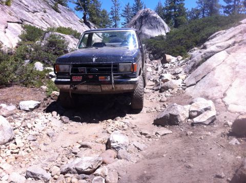 1990 Ford Bronco - Ford Bronco navigates a challenging rocky trail in a mountainous landscape.