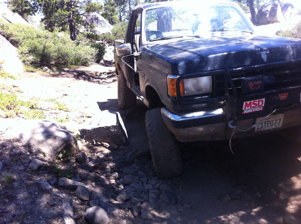 Ford F-Series truck on rocky trail, front right tire angled up