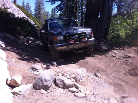 1990 Ford Bronco - This 1990 Ford Bronco navigates a challenging off-road path through a wooded area.