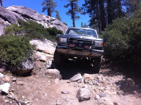 1990 Ford Bronco - This Ford Bronco is tackling a challenging off-road path with steep inclines and large rocks.