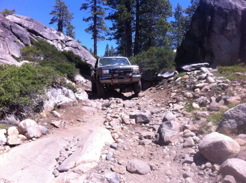 1990 Ford Bronco - A Ford Bronco tackles a challenging rocky terrain on a sunny day.